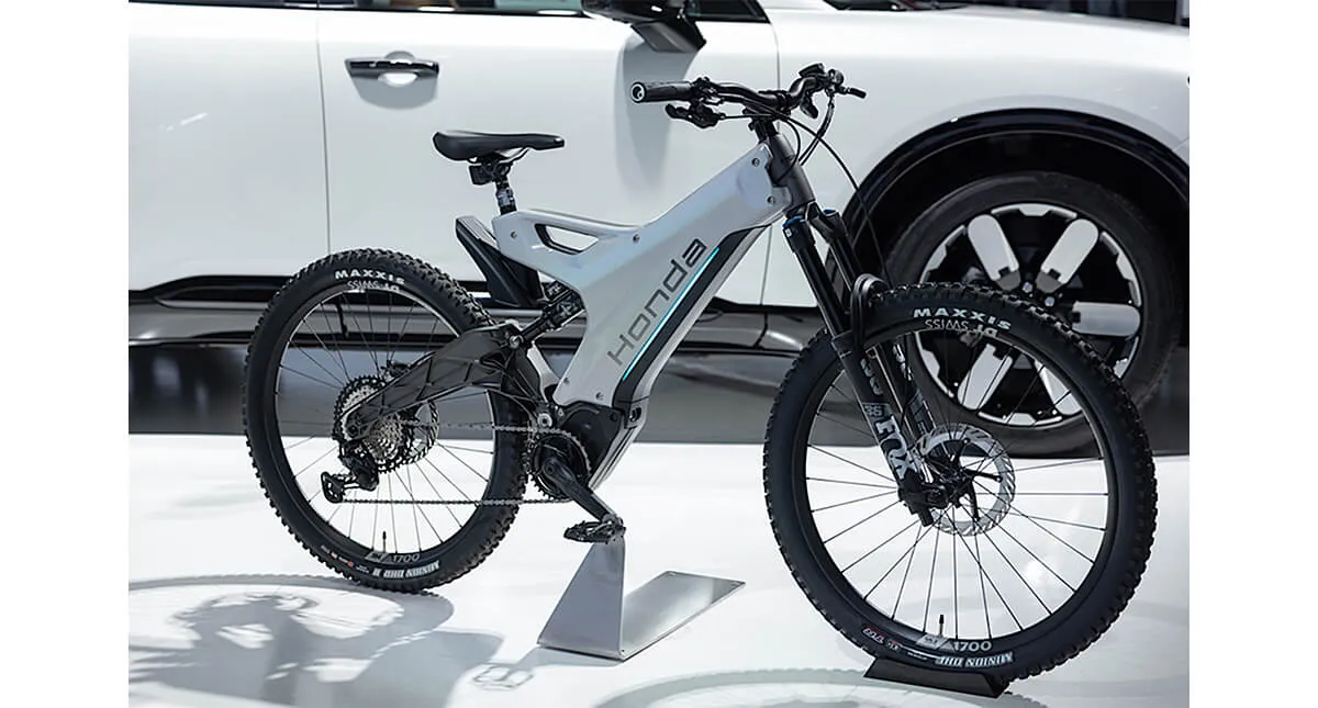 Bicicleta elétrica Honda e-MTB branca com camionete branca ao fundo