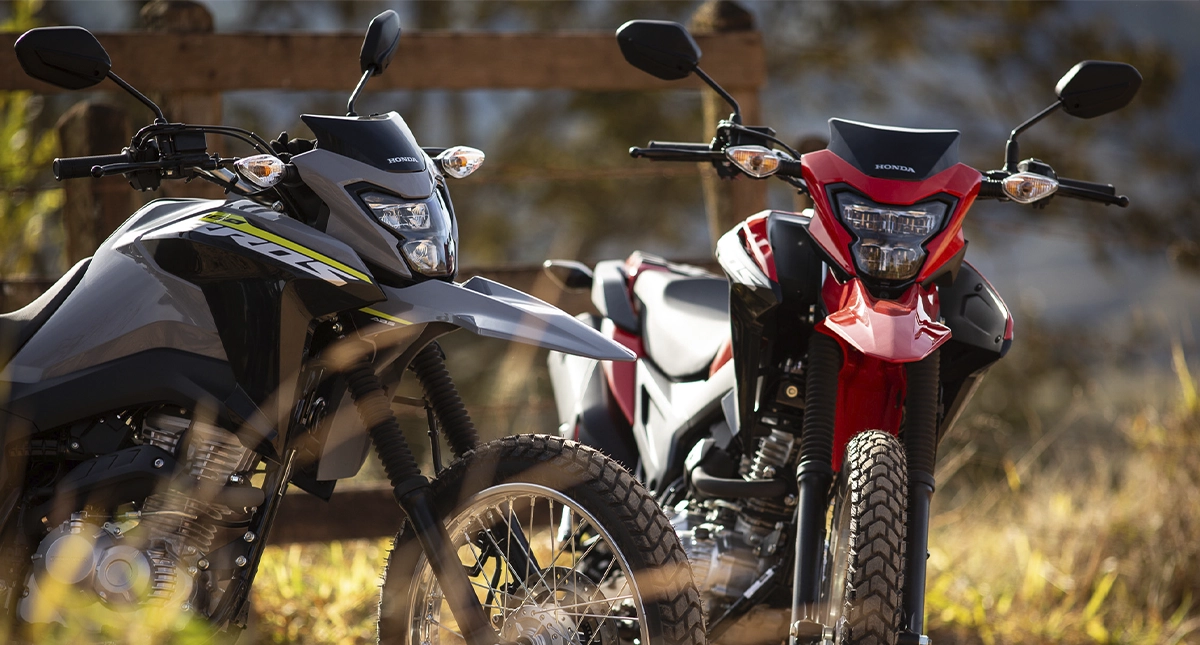 Motocicletas Honda Bros 160 2025 Cinza e Vermelha com grama e areia
