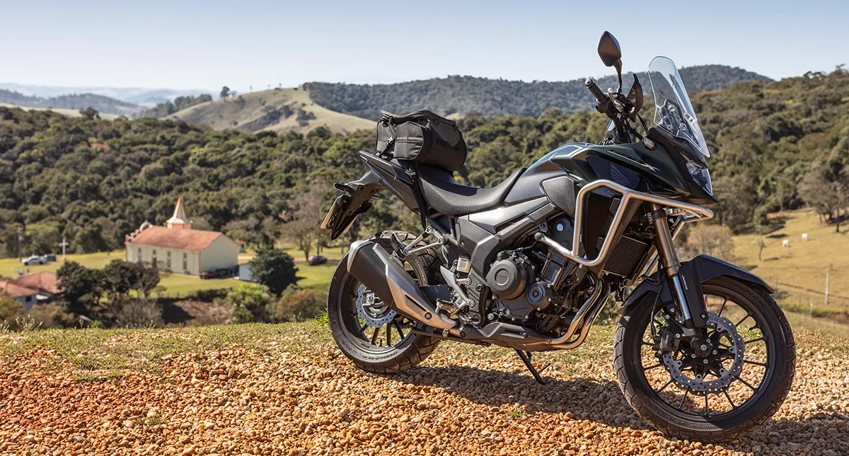 Motocicleta Honda CB 500X com cidade interiorana ao fundo