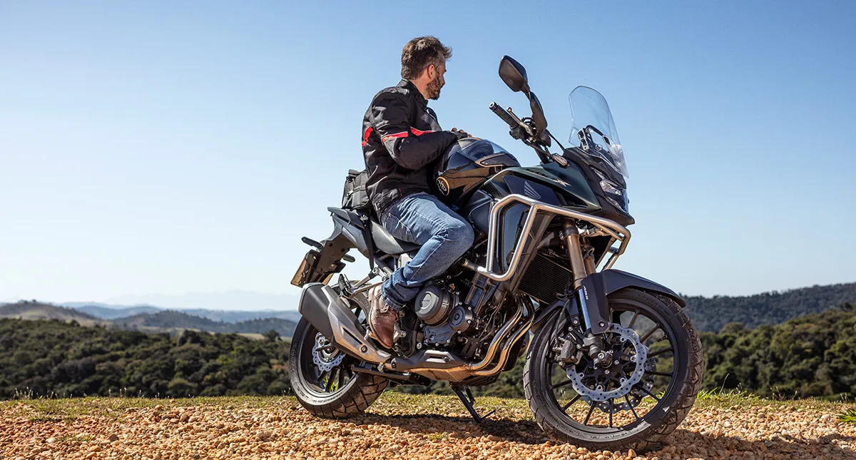 Piloto em sua motocicleta Honda CB 500X admirando paisagem