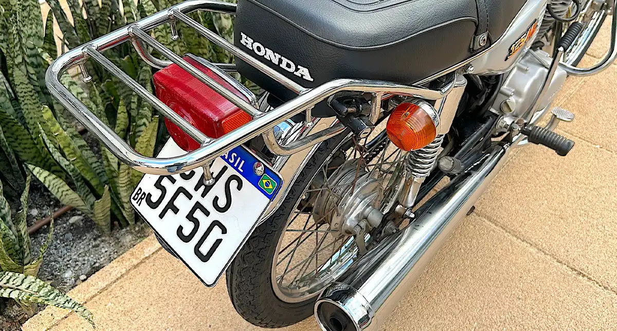 Detalhe da parte traseira da moto Honda 125 ML, mostrando o suporte e a iluminação