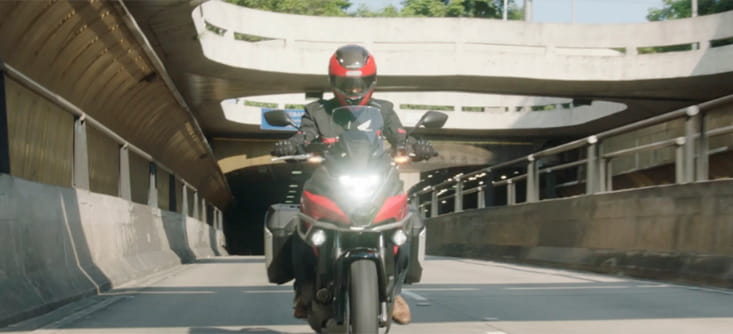 Motocilcista em uma moto vermelha passando por um tunel