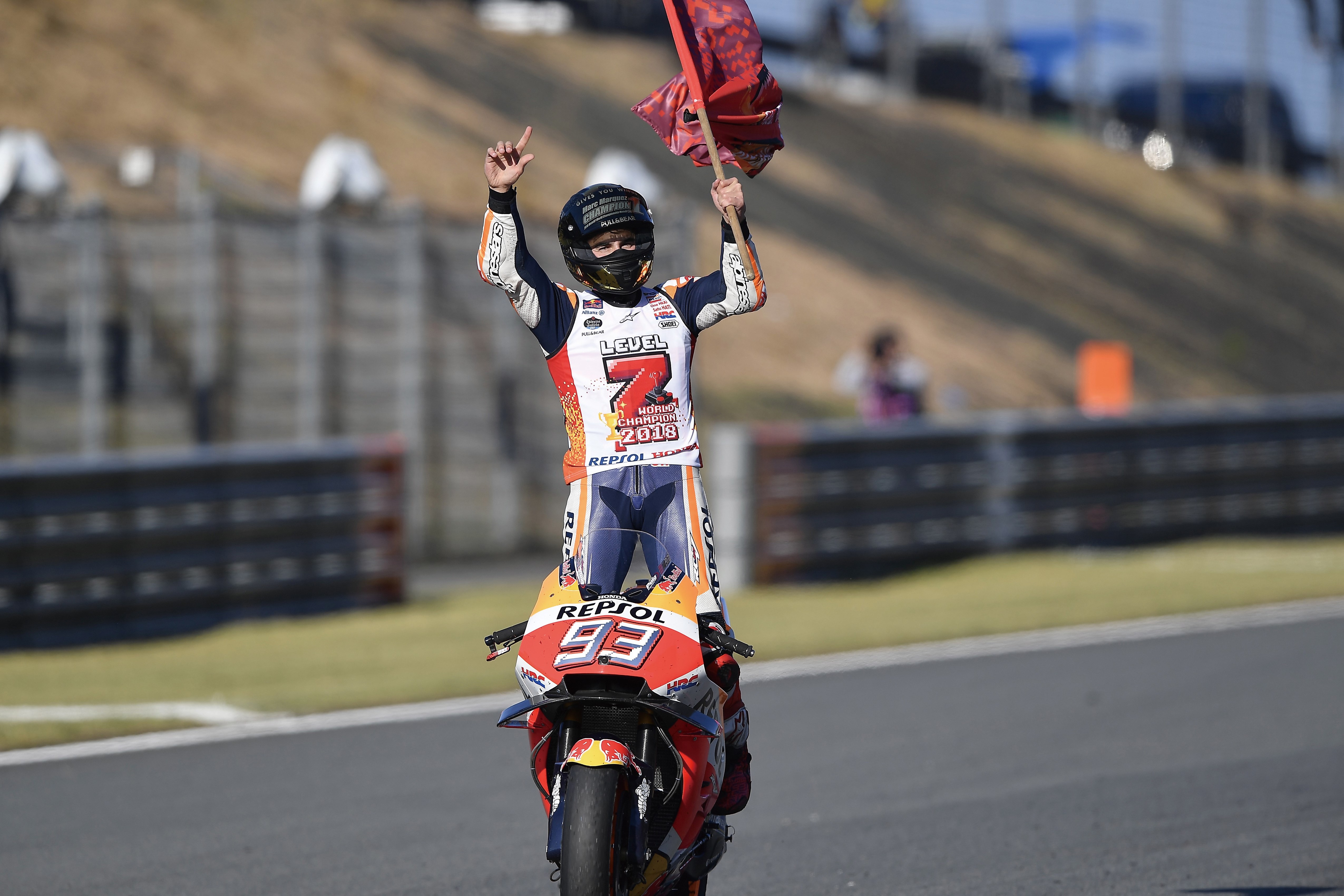 Piloto da Honda Marc Marquez em pé em moto segurando bandeira na mão esquerda no MotoGP
