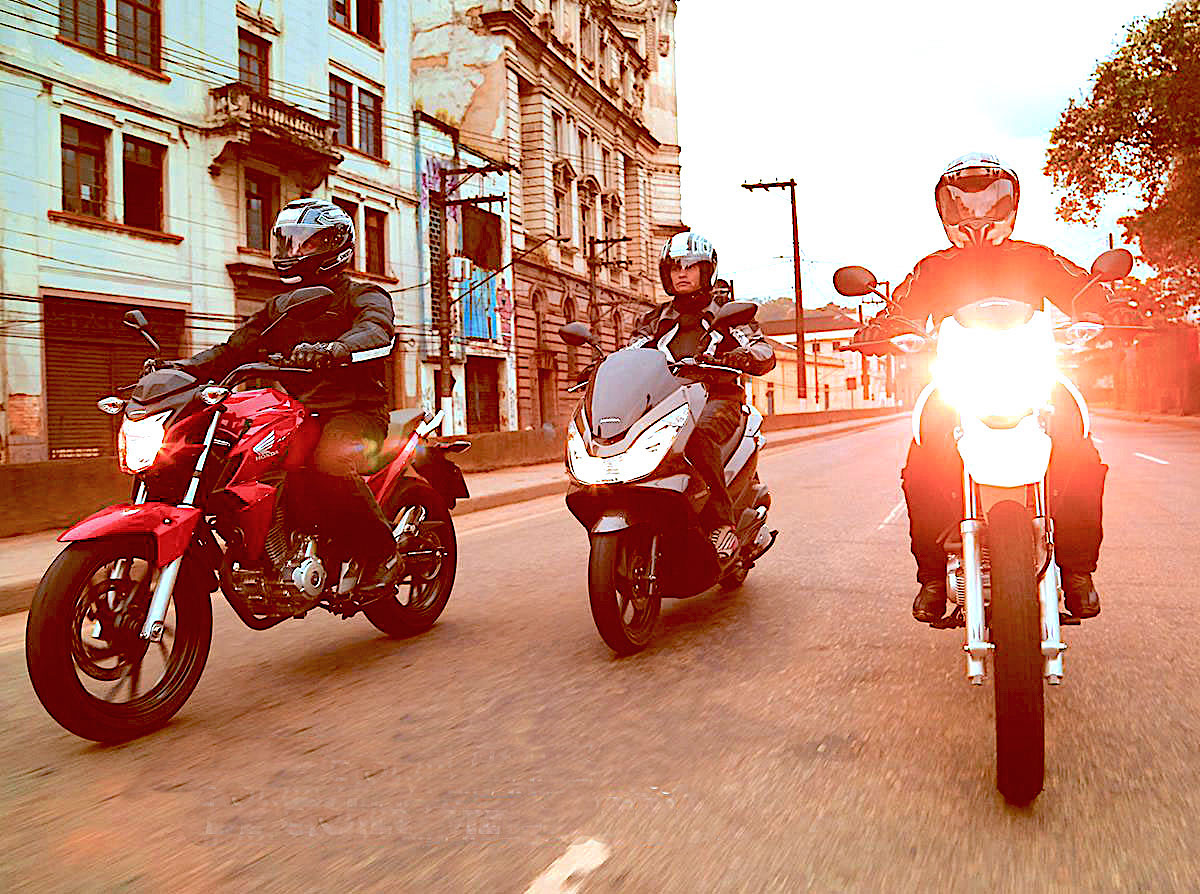 Três pessoas pilotando sua primeira moto Honda em ruas de cidade