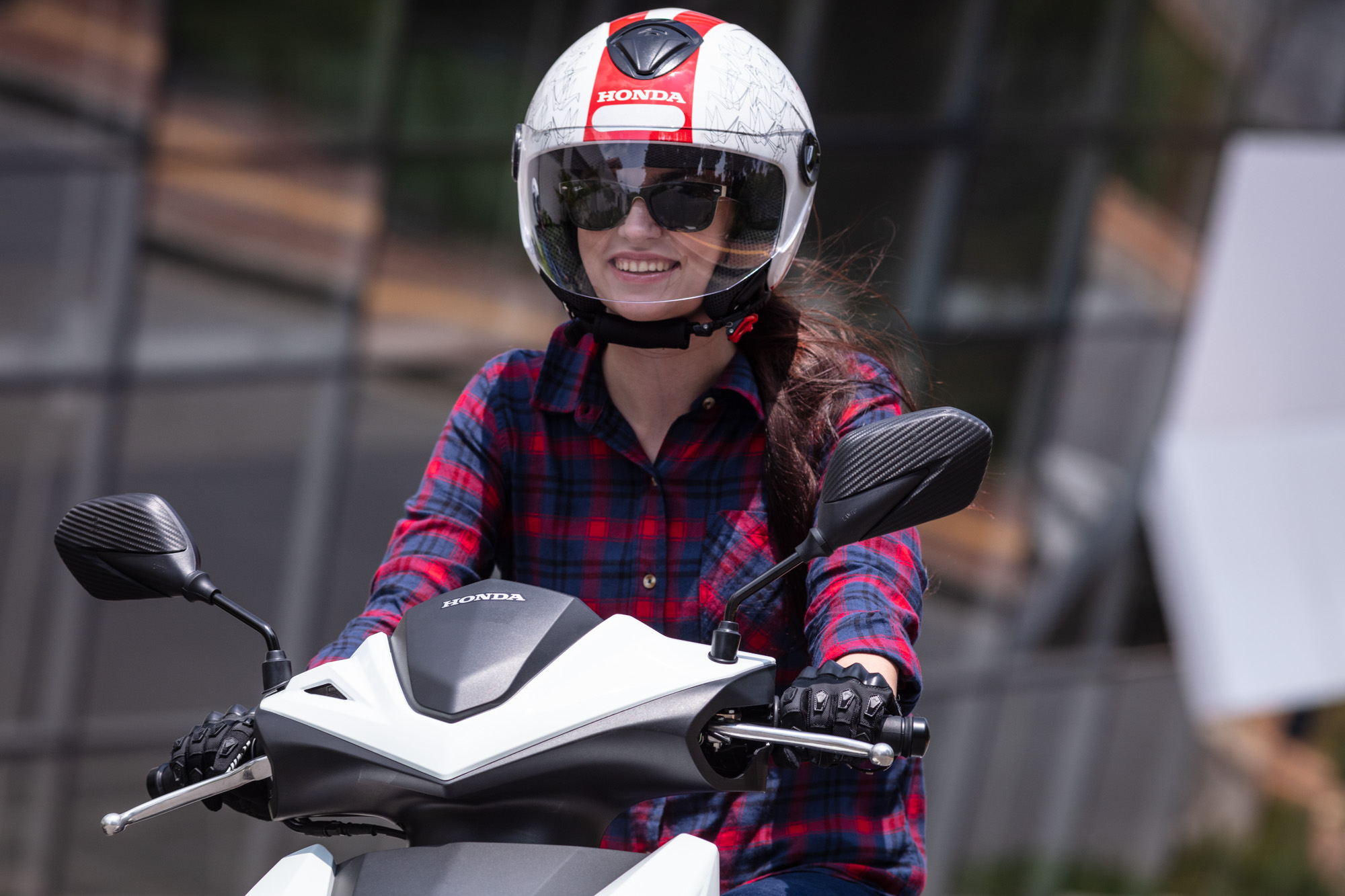Mulher pilotando moto Honda Elite 125 de luvas e capacete da Honda