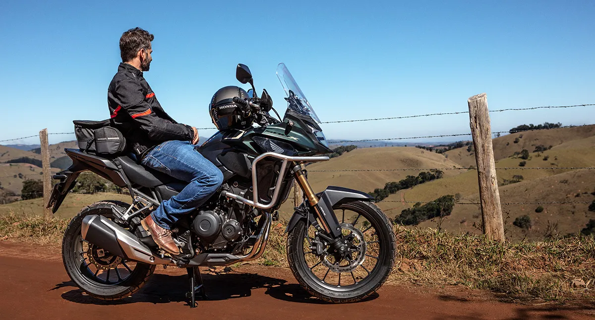 Piloto em sua motocicleta Honda CB 500X admirando paisagem de vale