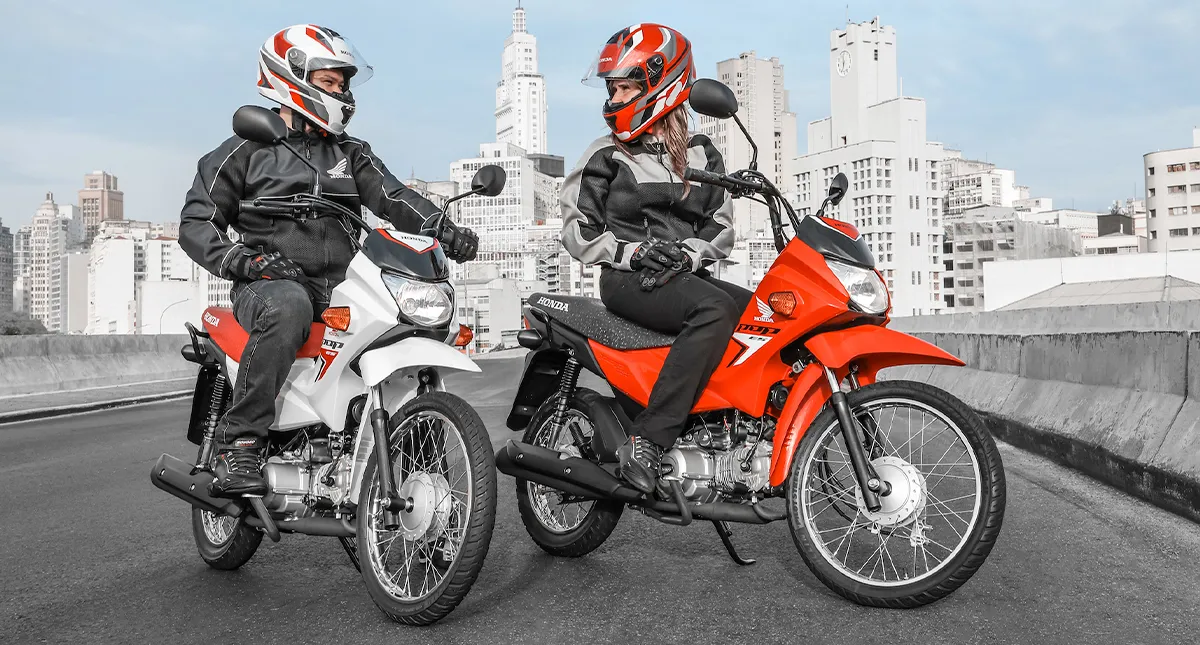 Pilotos um homem e uma mulher em suas motocicletas Honda Pop 110i ES em um viaduto