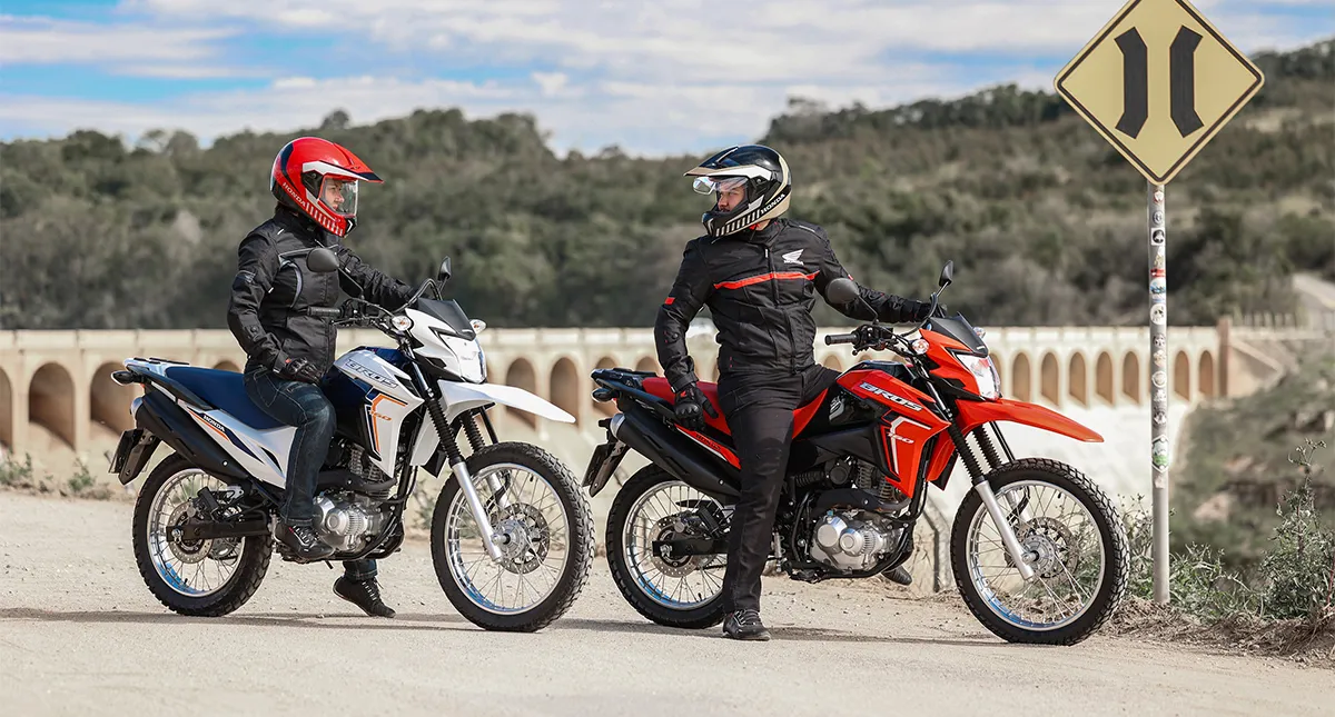 Dois pilotos em suas motocicletas Honda vestindo casaco e luvas de proteção