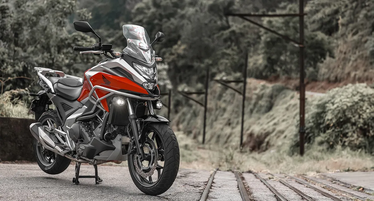 Motocicleta Honda NC 750X vermelha ao lado do trilho do trem