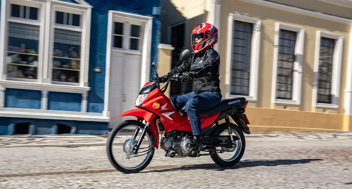 Motociclista pilotando a sua Honda POP 110i ES Vermelha na rua de paralelepípedo