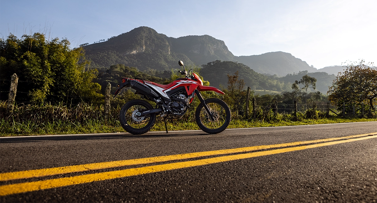 Motocicleta Honda XR 300L Tornado em estrada com montanha ao fundo