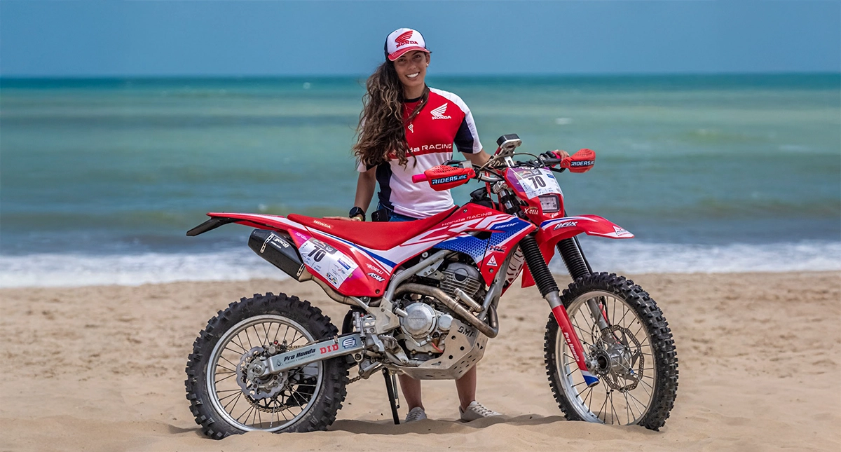 Barbara Neves posando com sua moto Honda na praia durante o Cerapio 2024