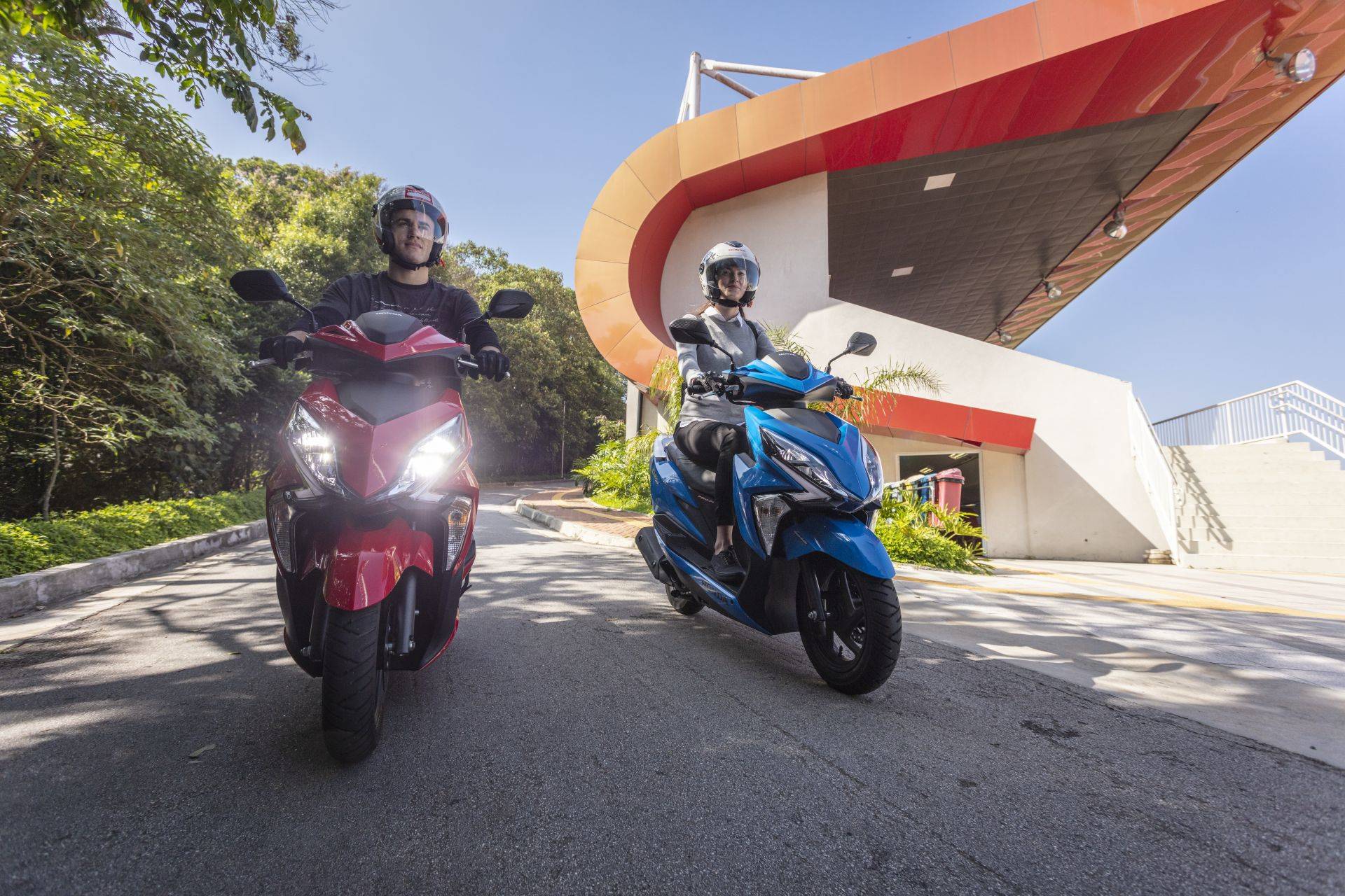 Homem em Honda Elite 125 vermelha e mulher em Honda Elite 125 azul