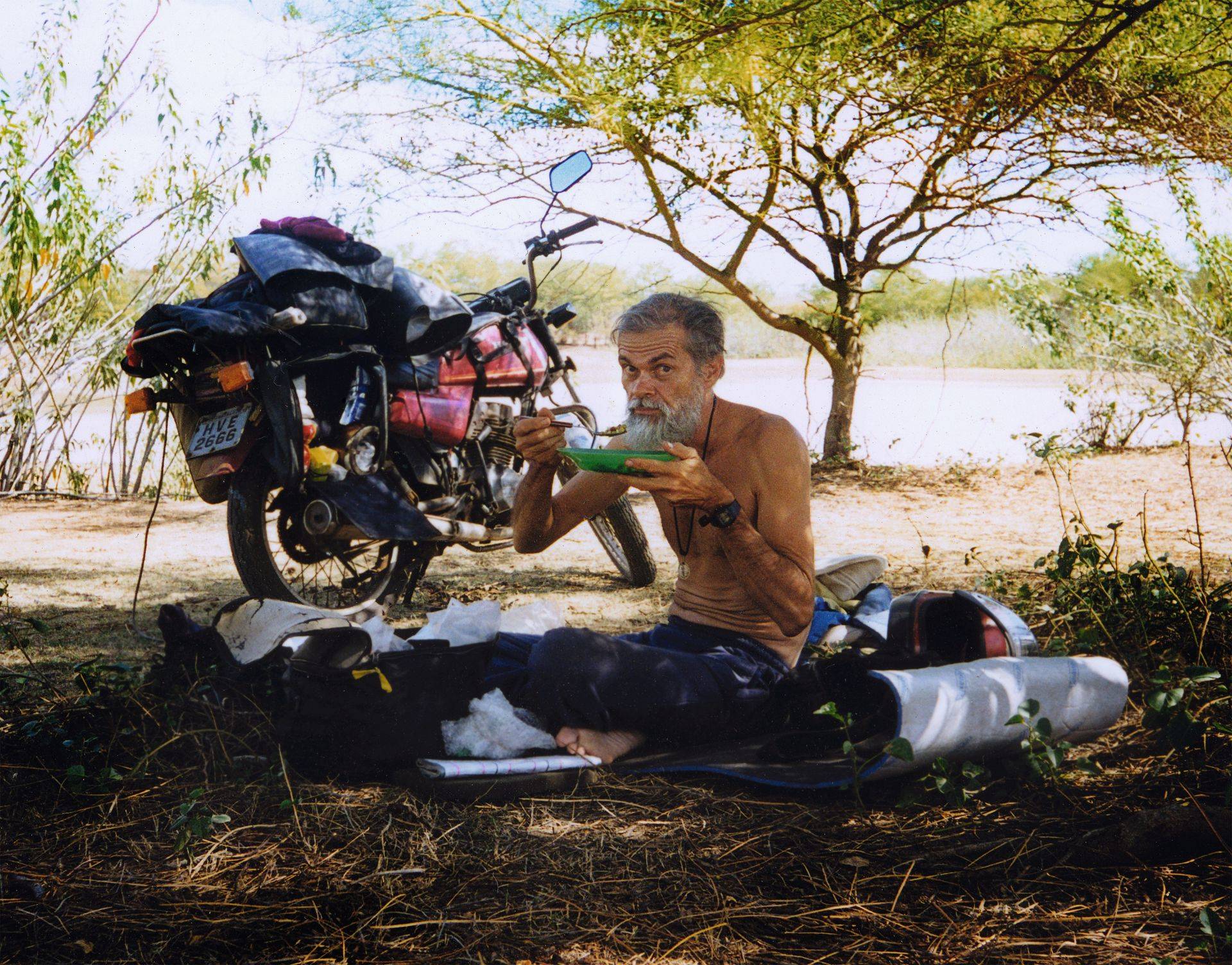 Fotógrafo José Albano segurando um prato de comida e a Honda ML 125 ao fundo