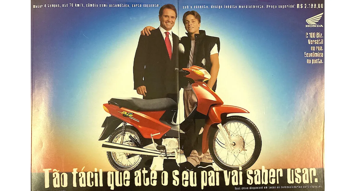 Propaganda antiga da Honda C100 Biz em revista, filho e pai atras da moto em cor vermelha 