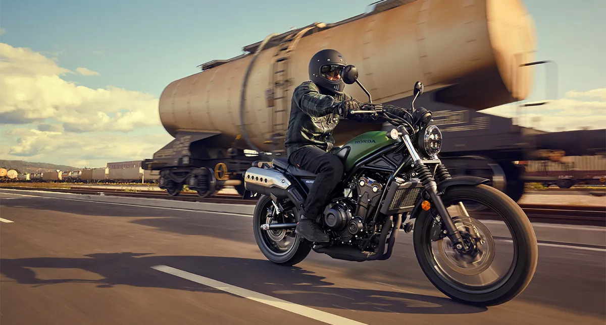 Motociclista Pilotando sua Moto CL 500 com caminhão ao fundo