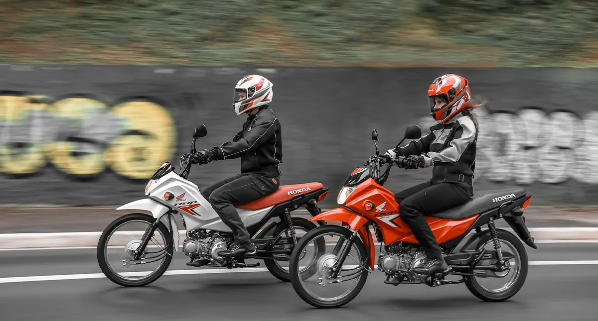 Pilotos um homem e uma mulher em suas motocicletas Honda Pop 110i ES em movimento