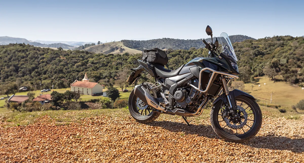 Motocicleta Honda CB 500X com cidade interiorana ao fundo