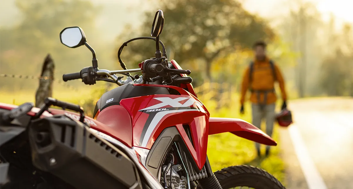 Detalhe motocicleta Honda XR 300L Tornado 2025 em destaque com homem ao fundo