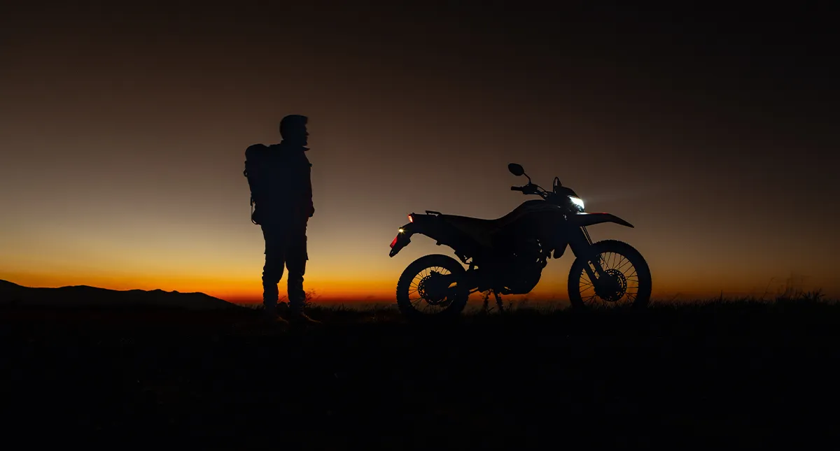 Motocicleta Honda XR 300L Tornado 2025 no anoitecer com homem ao lado