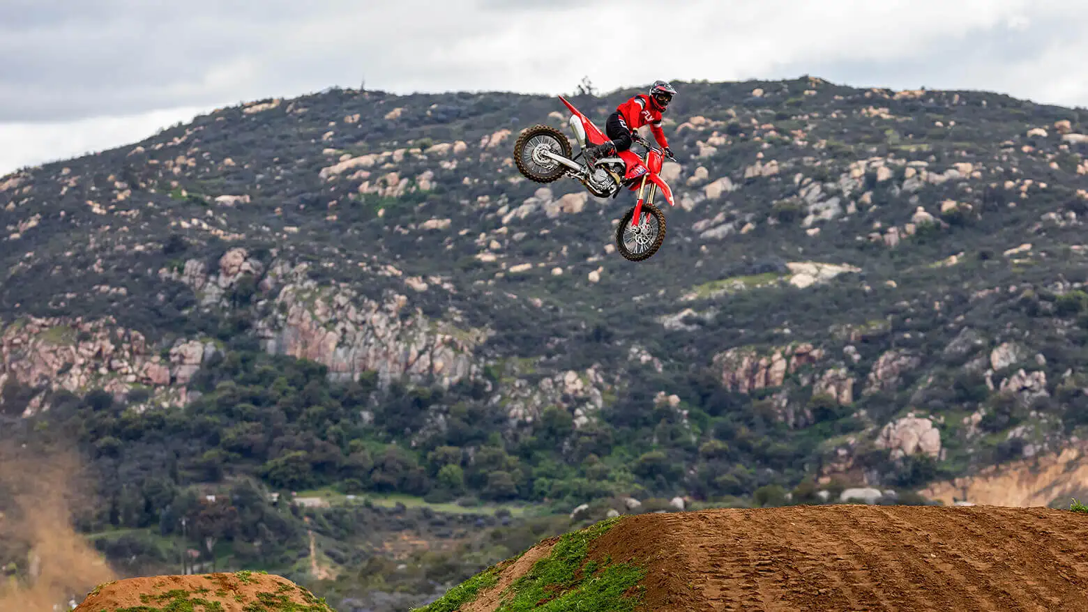 Piloto saltando em estrada de terra com sua moto Honda CRF 450 