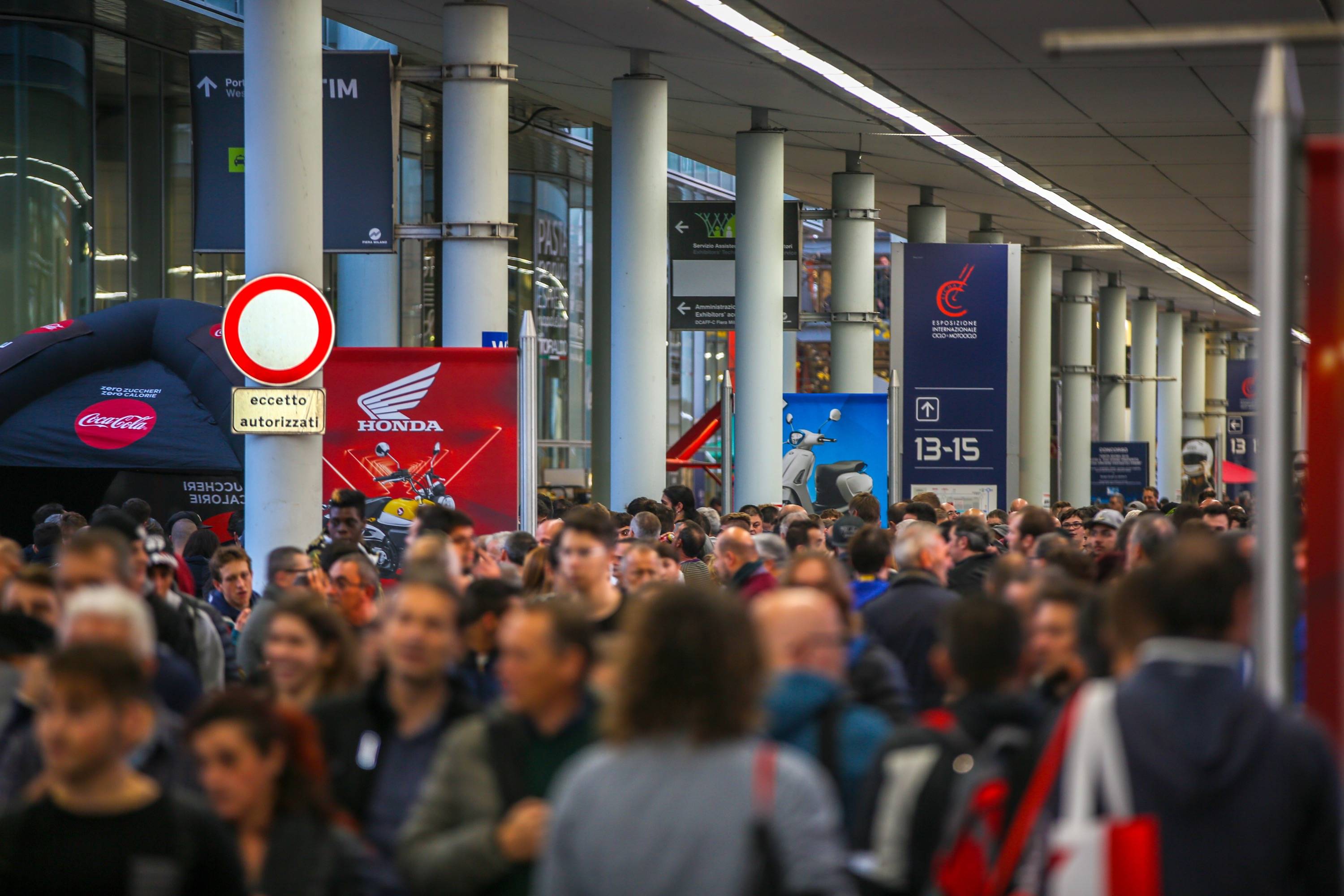 Corredor do salão de moto de Milão, o EICMA, com diversas pessoas caminhando