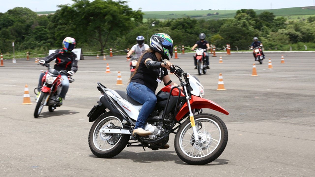 Mulher fazendo curva com a Honda Bros 160 em aula de auto moto escola