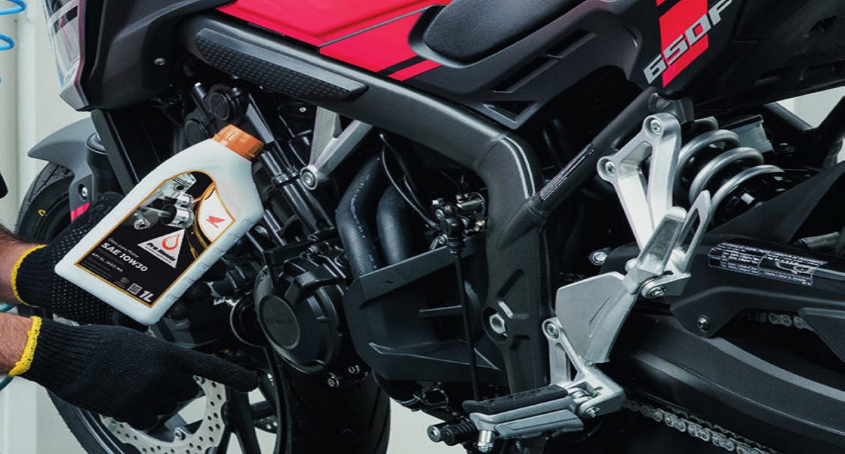 Mecânico segurando lubrificante e detalhe do motor da moto Honda CB 650F