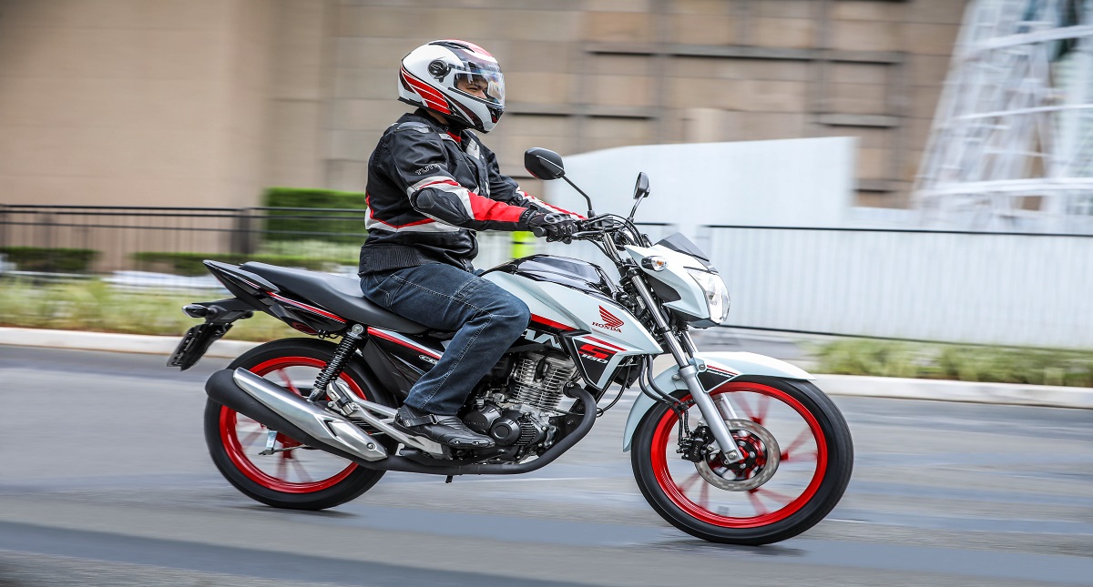 Homem pilotando moto Honda CG 160 Titan em rua de cidade