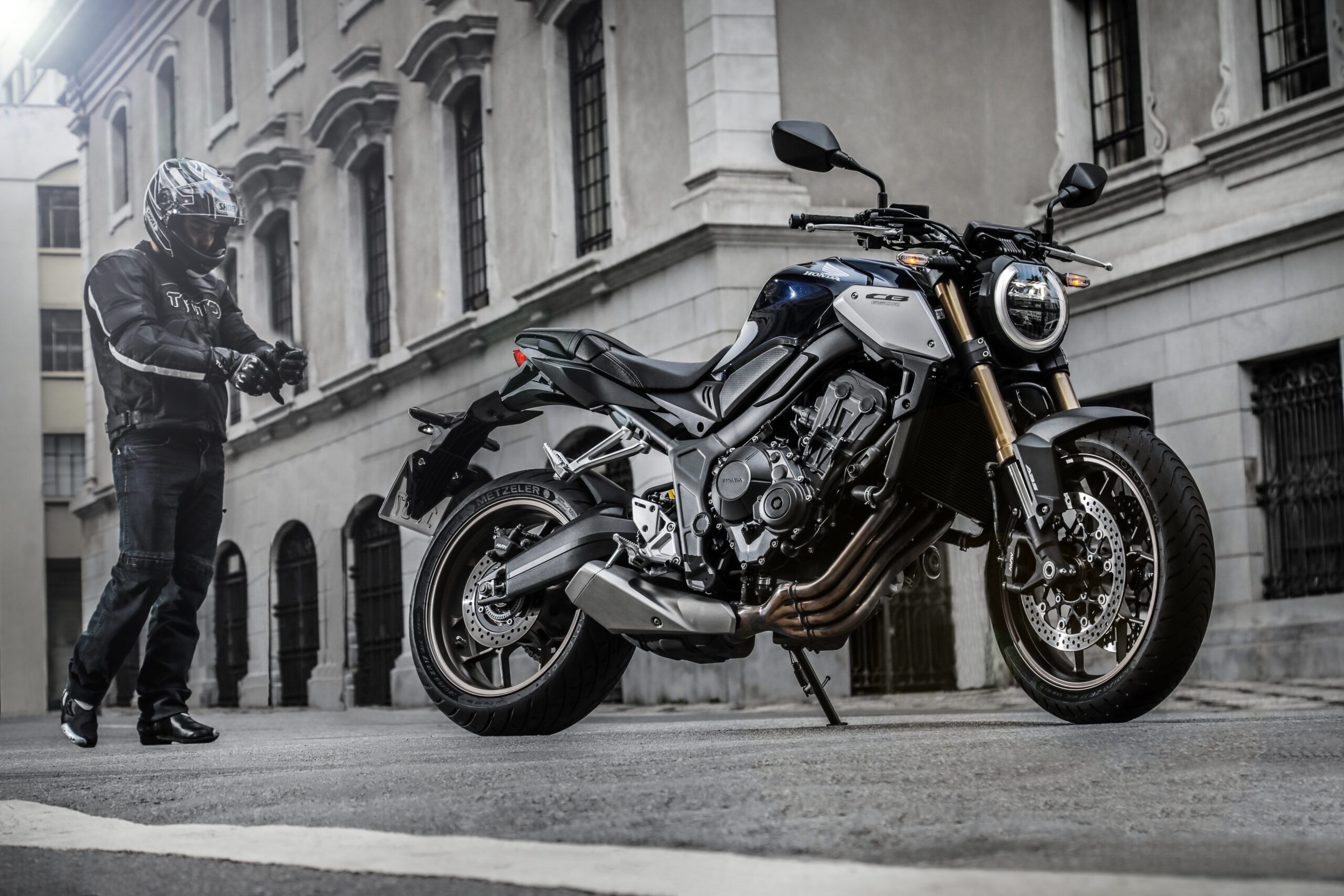 Motociclista arrumando luva ao lado da moto Honda CB 650R 