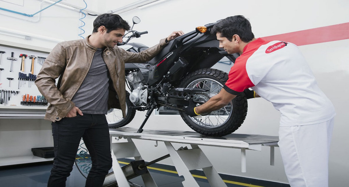 Homem olhando mecânico mexendo em corrente de moto Honda