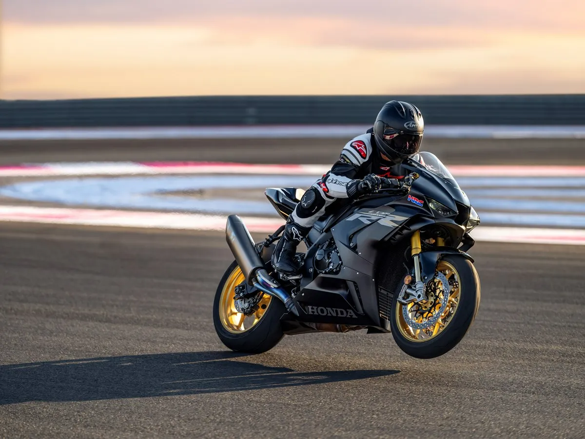 Piloto com capacete e roupa de proteção, empinando sua moto Honda CBR 1000RR-R Fireblade SP em pista de corrida