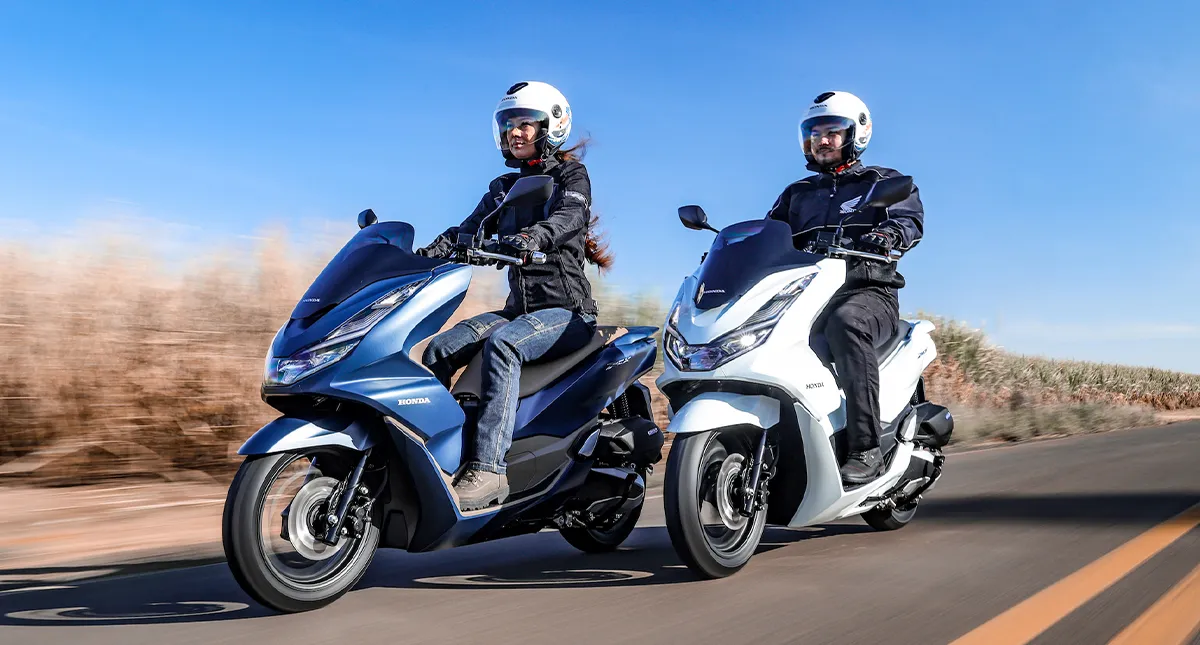 Casal pilotando suas scooters PCX modelo 2023 na cor azul metálico e branca perolizado