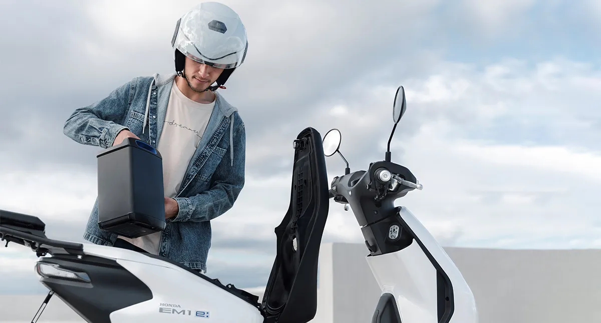 Motociclista Colocando Bateria na Scooter Elétrica Honda Em1 e