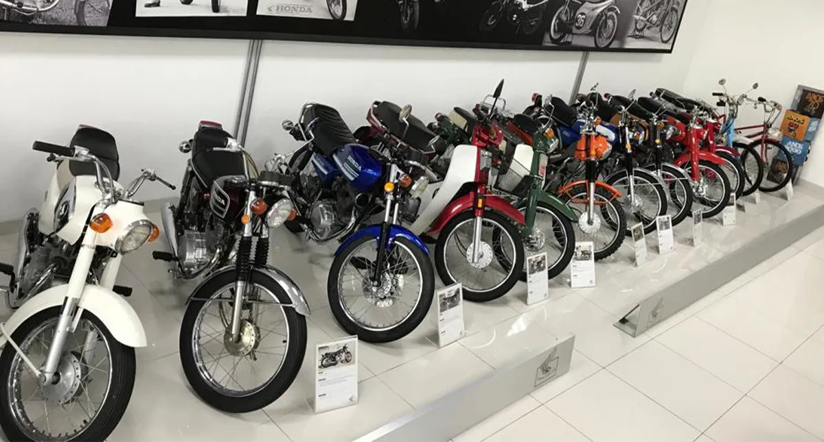 Motos Honda expostas no museu da Honda com painel de notícias ao fundo