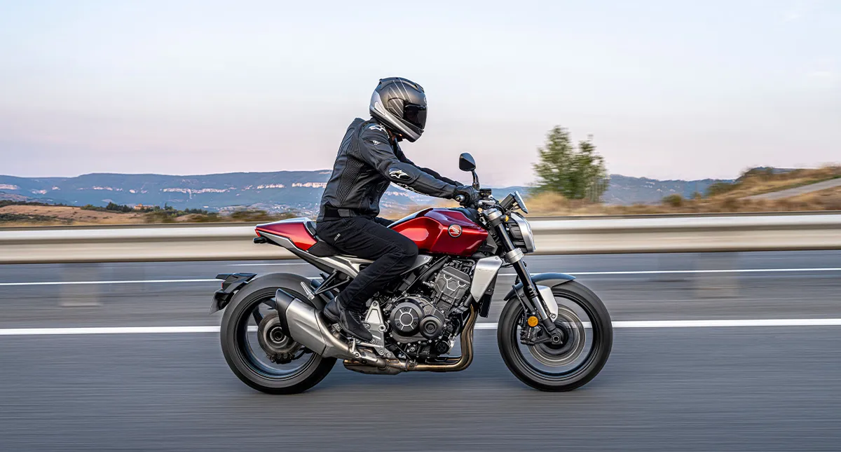 Homem de Jaqueta Preta Pilotando Moto Honda CB 1000R Vermelha em Estrada