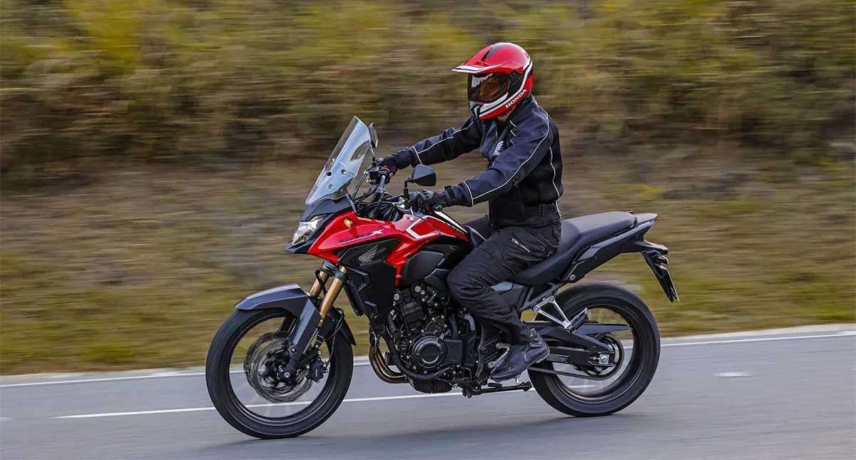 Homem em moto Honda CB 500X vermelha na estrada de asfalto