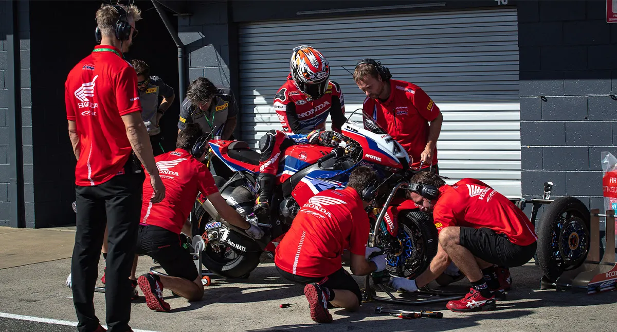 Equipe HRC mexendo em moto onde piloto está sentado