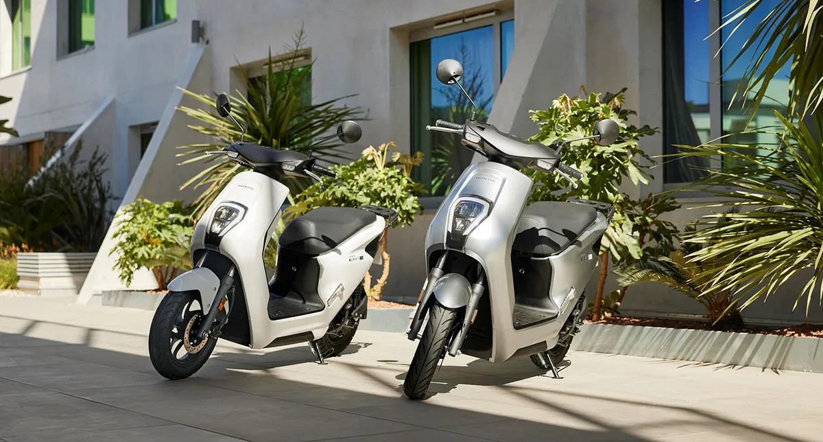 Duas Honda EM1 estacionadas, uma branca e uma prateada