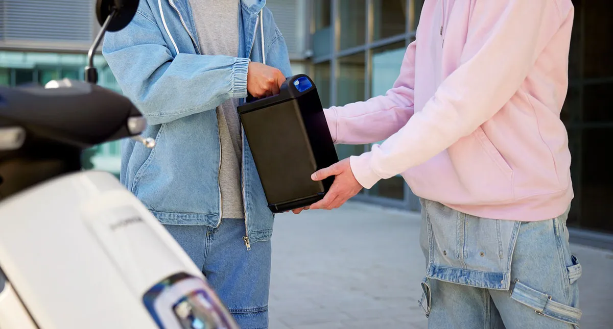 Duas pessoas segurando a bateria de sistema Honda Mobile Power Pack e