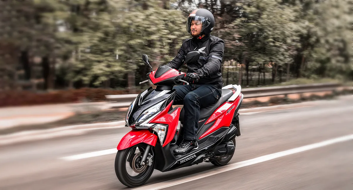 Homem pilotando sua moto Scooter Elite Vermelha na estrada