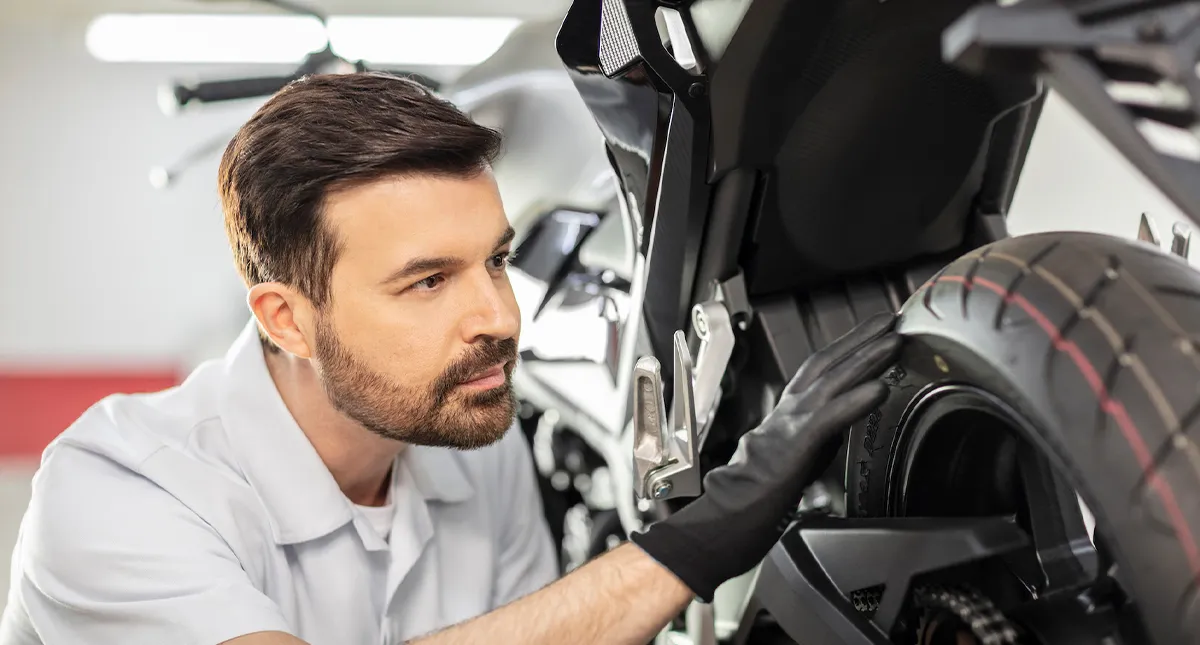 Colaborador avaliando detalhes do pneu no Serviço de pós venda em Concessionária Honda Motos