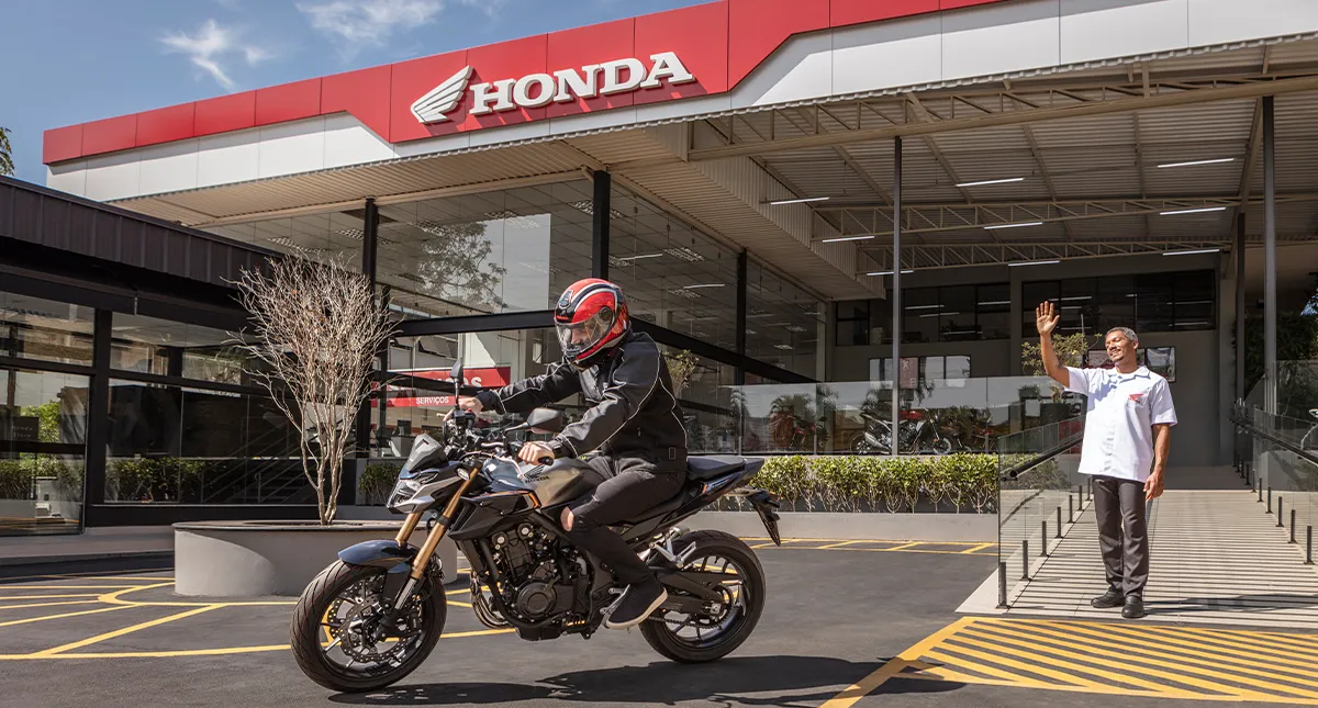 Concessionária Honda com colaborador e motociclista a frente