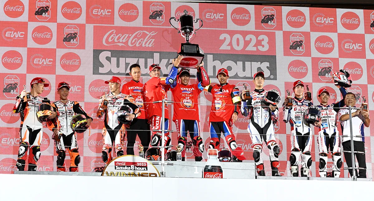 Pilotos do Team HRC no pódio de Suzuka com erguendo o troféu 