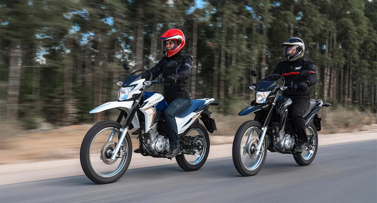 Dois pilotos na estrada em suas Motocicletas Honda NXR 160 Bros ESDD 2024, uma mulher em uma Bros branca e um homem em uma Bros Preta