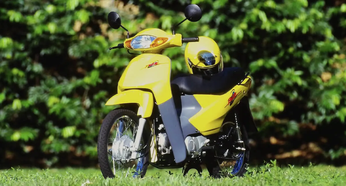 Motocicleta Honda C100 Biz Amarela com capacete encima do banco