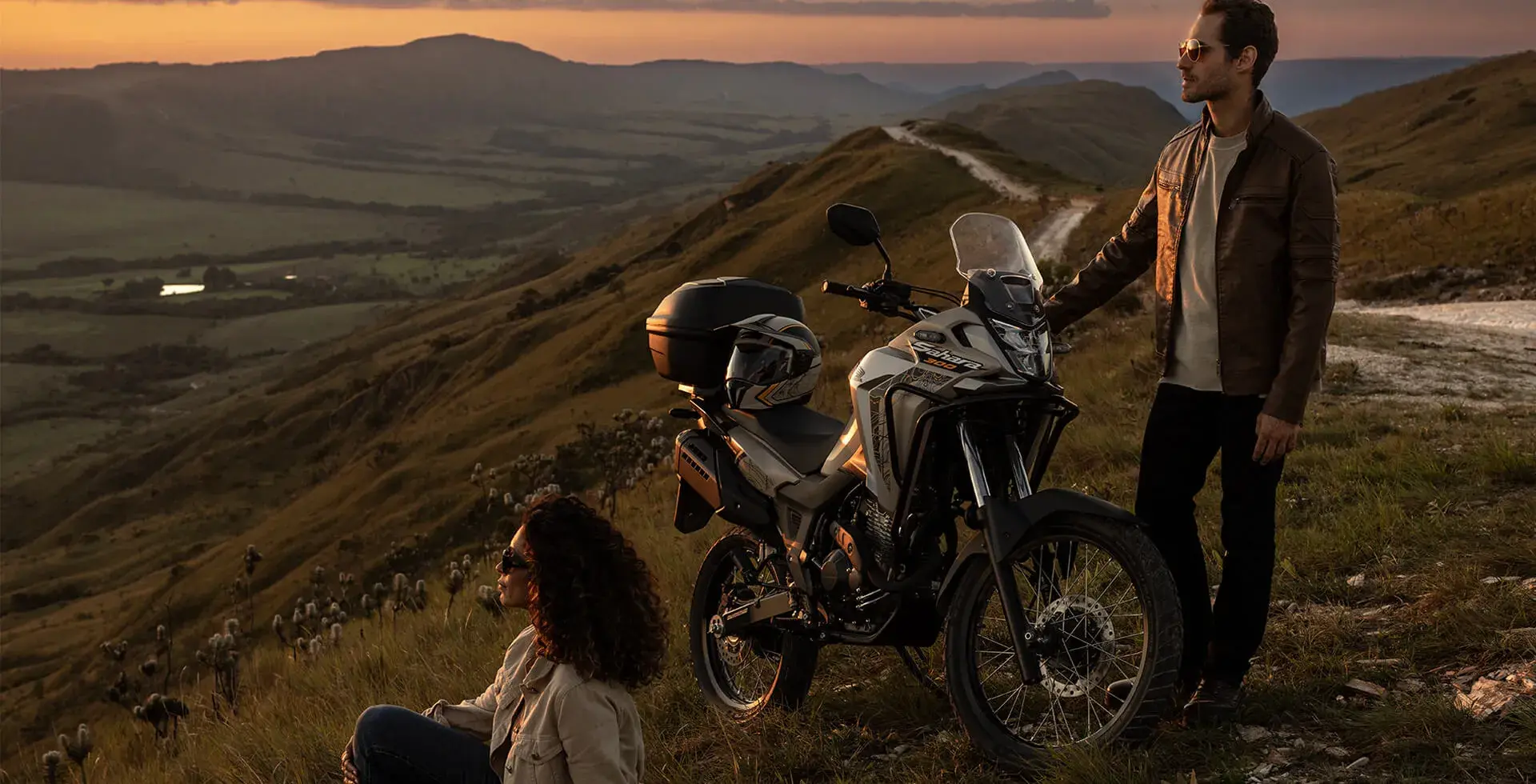 Homem observando o pôr do sol ao lado da Honda Sahara 300