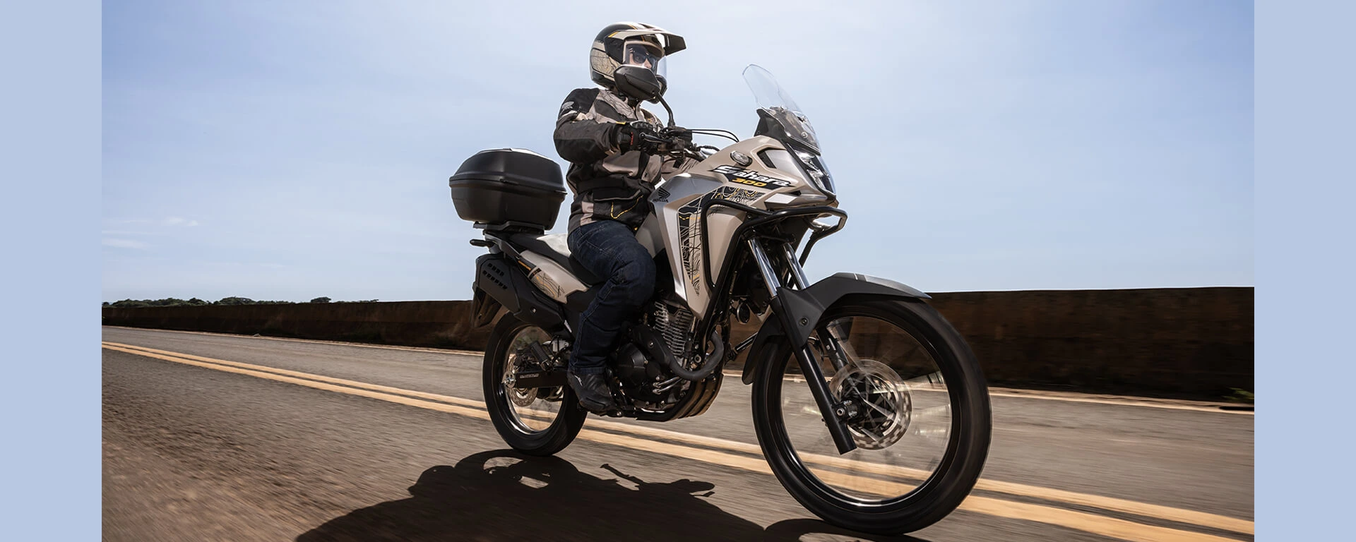 Homem em moto exaltando design da Honda Sahara 300 em estrada de asfalto