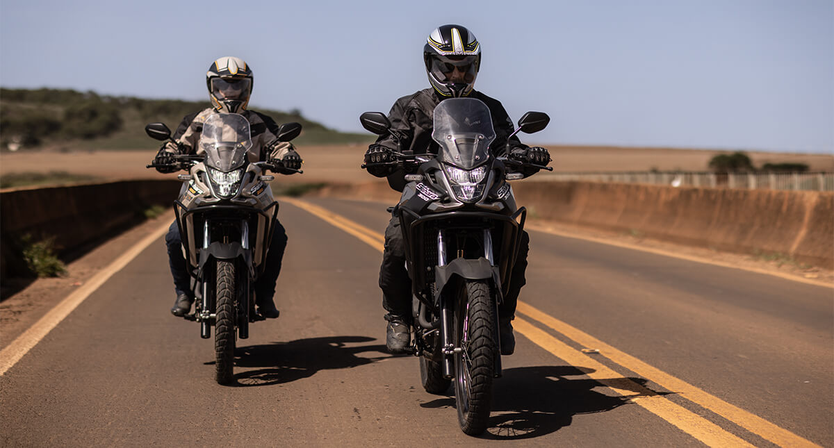 Pilotos em estrada de asfalto com as motocicletas Honda Sahara 300 