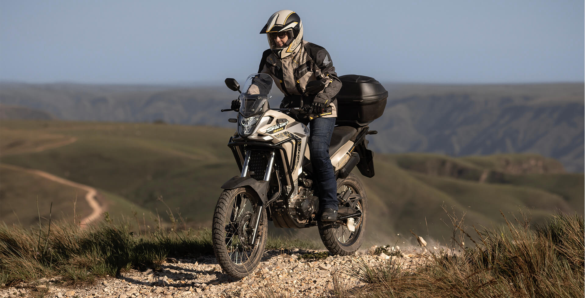 Piloto em pé em moto Honda Sahara 300 Adventure em trilha de areia